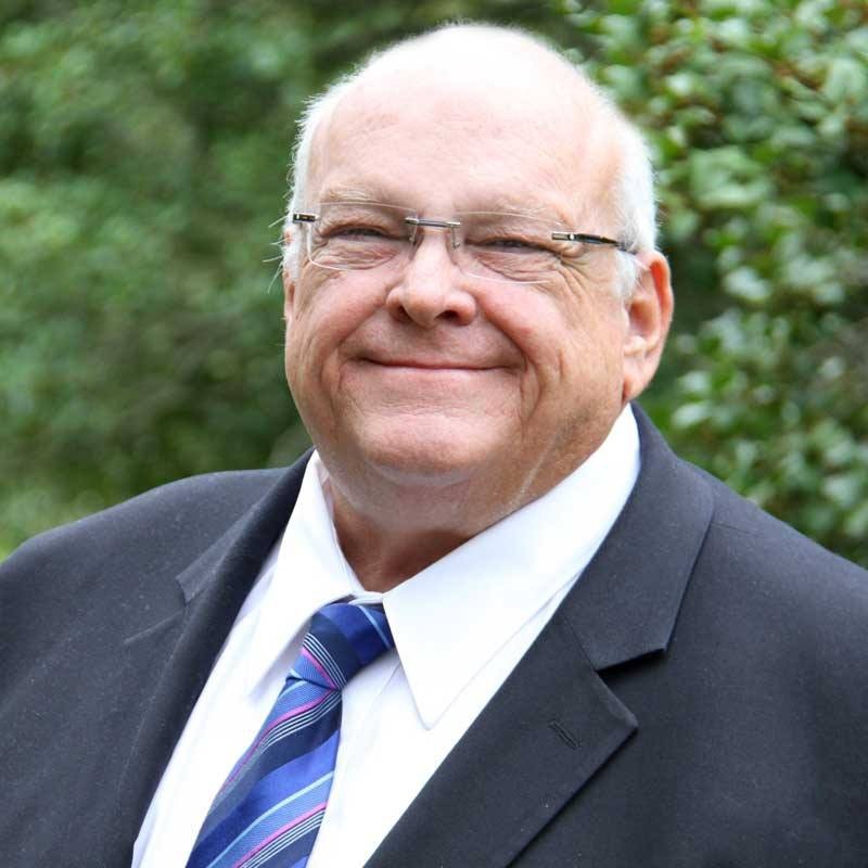 Smiling elderly man in a suit and tie outdoors.