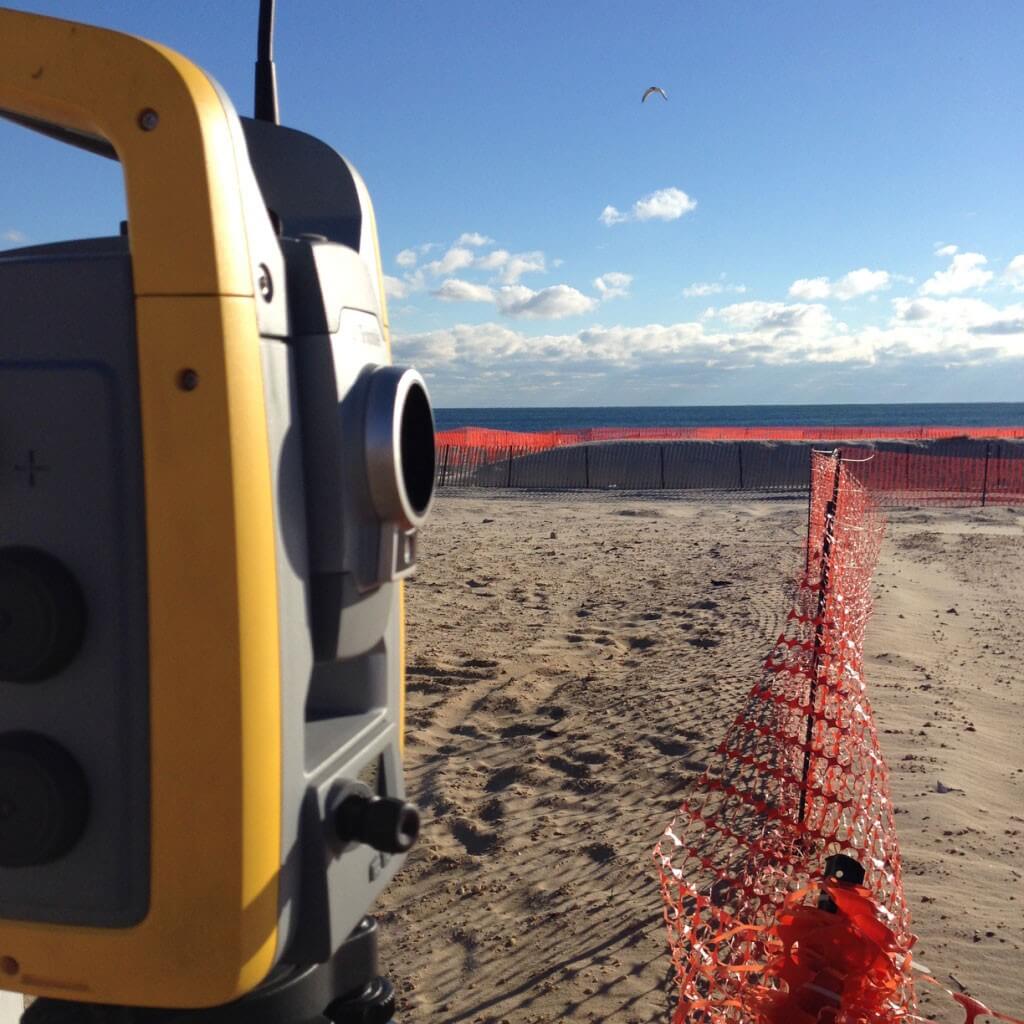Survey equipment on a beach near ocean.