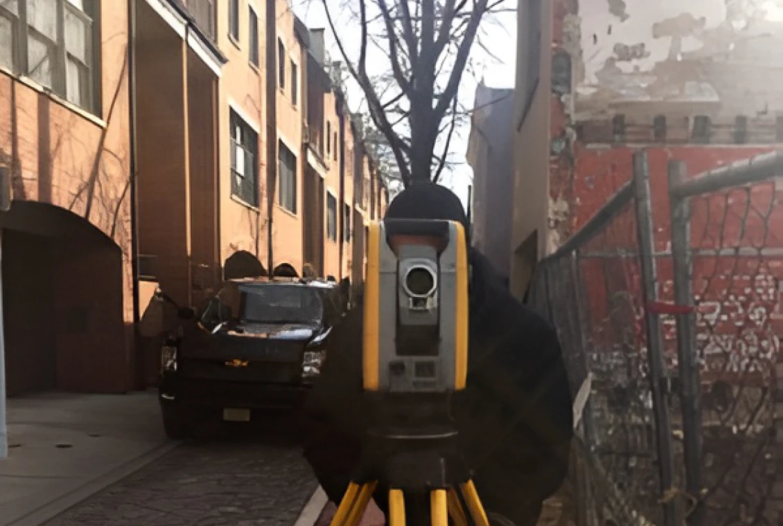 Man operating surveying instrument outdoors