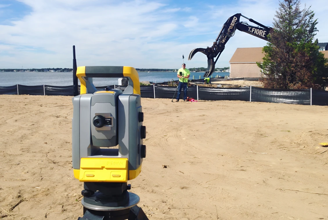 Construction site with surveying tool and excavator
